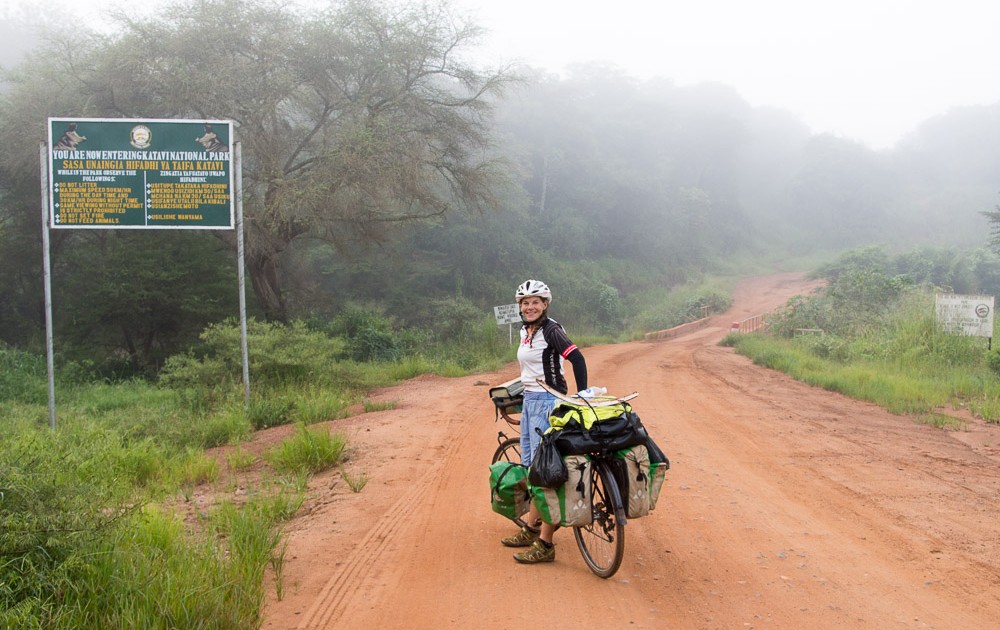 London to Cape Town Cyclists pose by the entrance sign of the Katavi National Park in Uganda as they